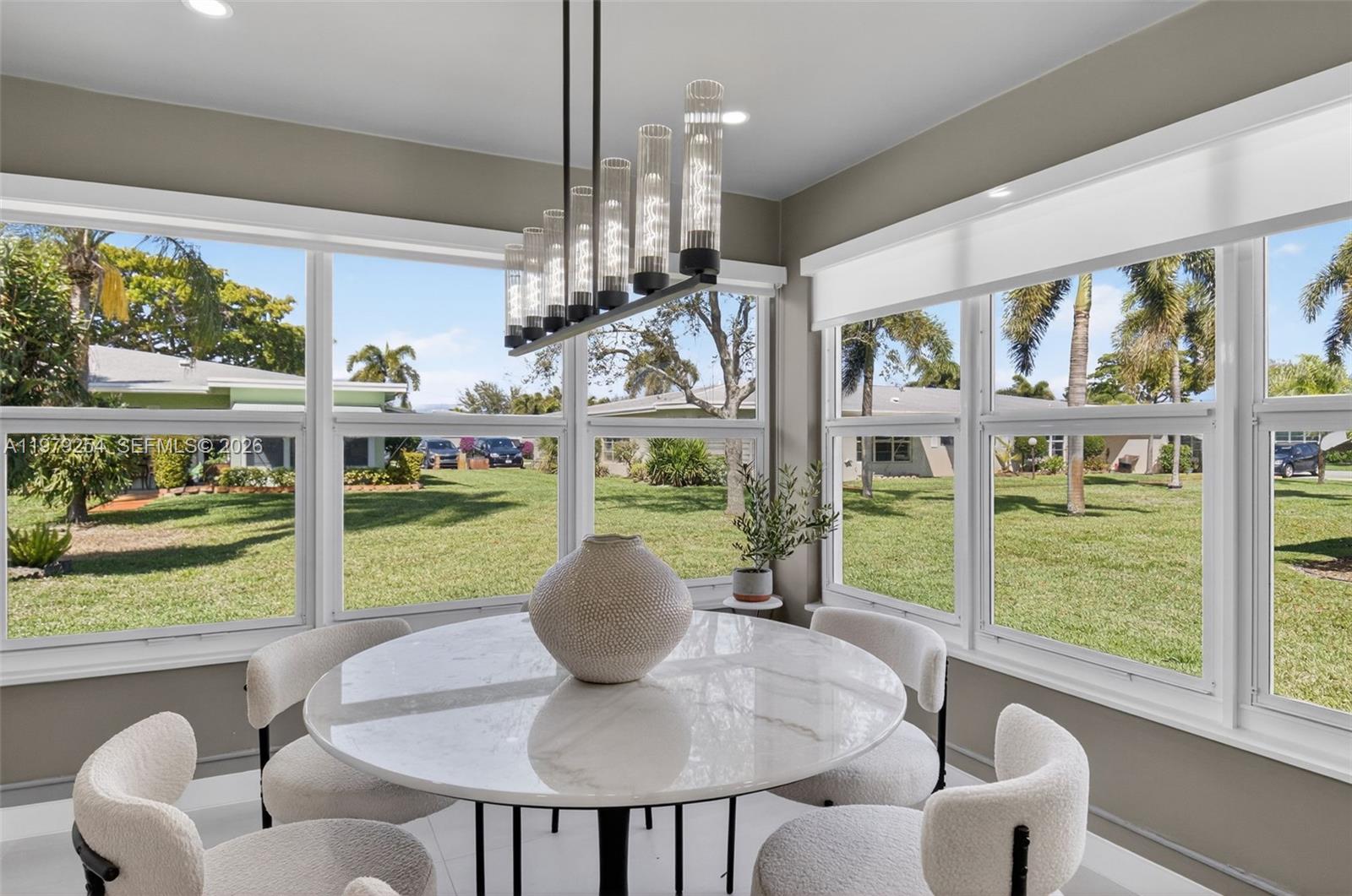 A dining area features a round marble table, modern chairs, and large windows overlooking lawns — 3240 Park Ln # D, Boynton Beach FL 33435, BOYNTON BEACH, FL