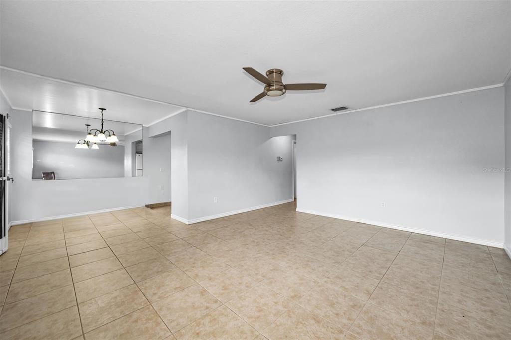 A spacious living room features light-colored tile flooring, white walls, and a ceiling fan — 11905 BAYONET LANE, NEW PORT RICHEY, FL