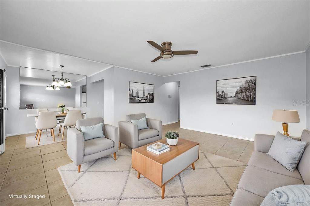 A living room with tile floors, a ceiling fan, and a dining area with mirrors — 11905 BAYONET LANE, NEW PORT RICHEY, FL