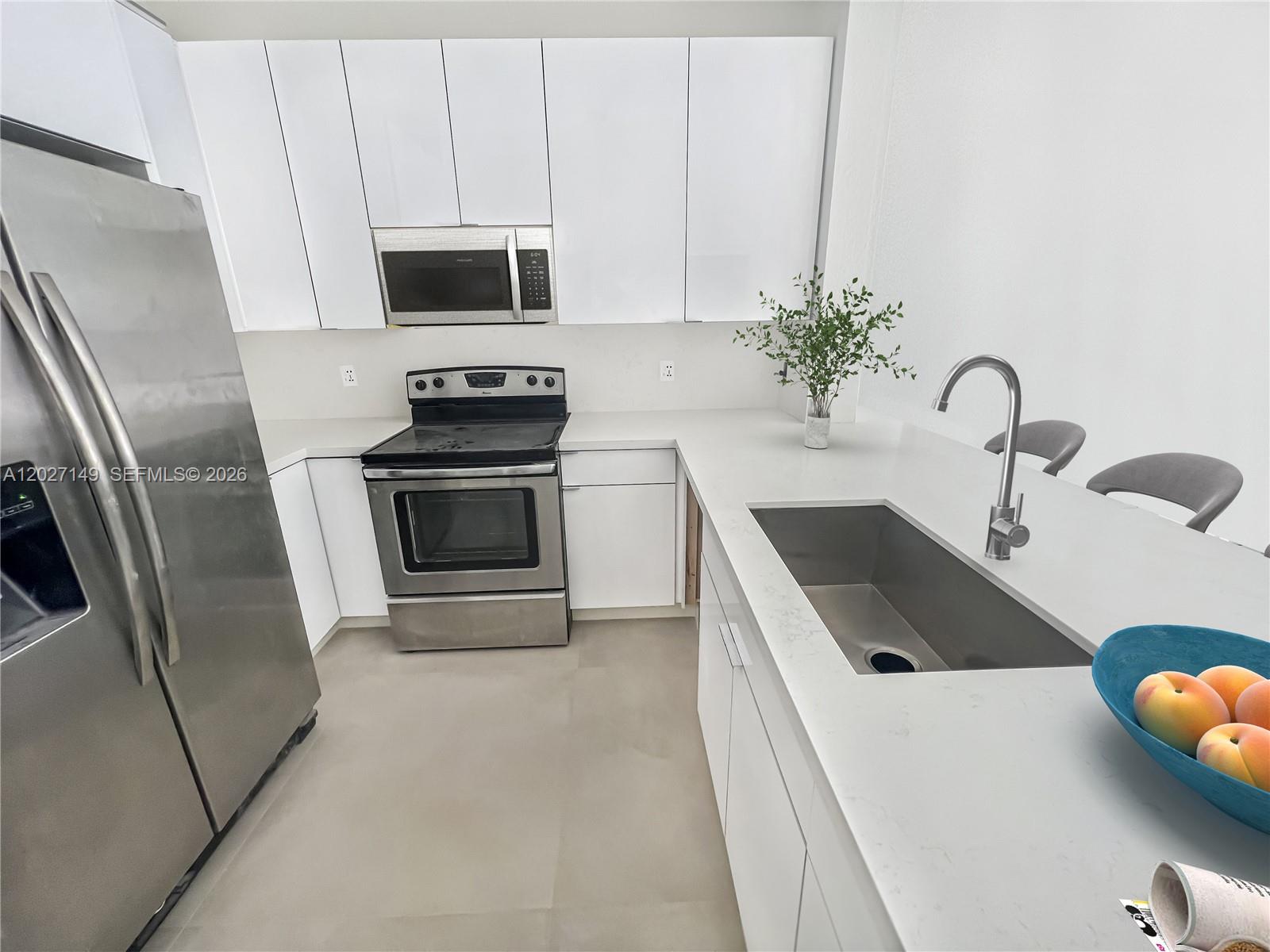 A modern kitchen features white flat-panel cabinets, stainless steel appliances, and a quartz countertop island — 10754 NW 85th Ter # 34, Doral FL 33178, DORAL, FL