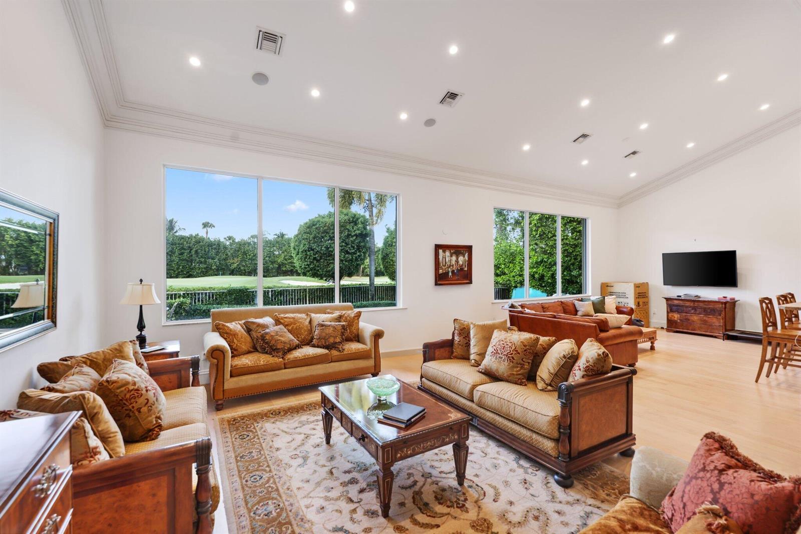 A spacious living room features multiple sofas, a coffee table, and large windows overlooking greenery — 7355 Mandarin Drive, Boca Raton FL 33433, BOCA RATON, FL