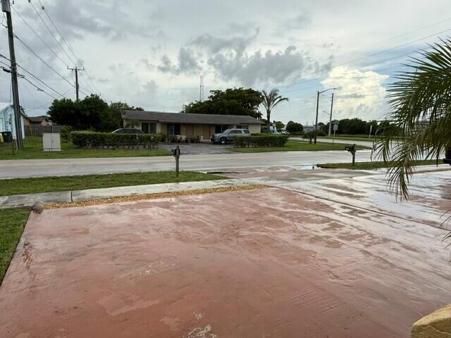 A view of a residential street featuring a single-story house and a wet driveway — 103 NE 28th Street, Boca Raton FL 33431, BOCA RATON, FL