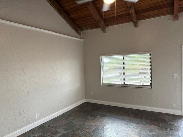 A room with a vaulted wood-beam ceiling, textured walls, and dark stone tile flooring — 103 NE 28th Street, Boca Raton FL 33431, BOCA RATON, FL