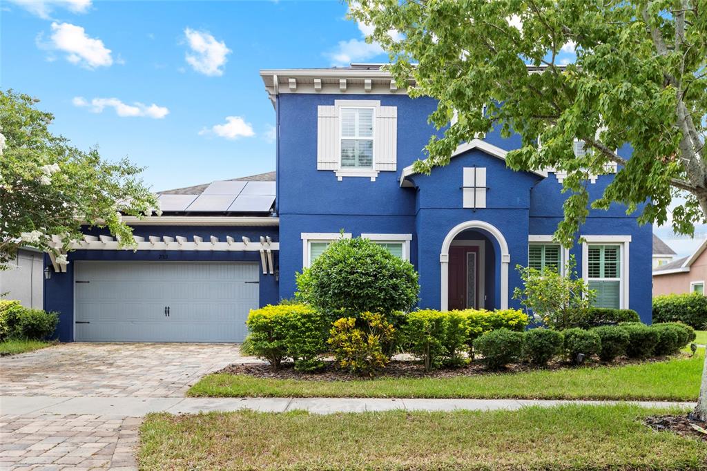 A two-story blue house with a garage, solar panels, and a front garden — 7013 ARTESIAN COURT, APOLLO BEACH, FL