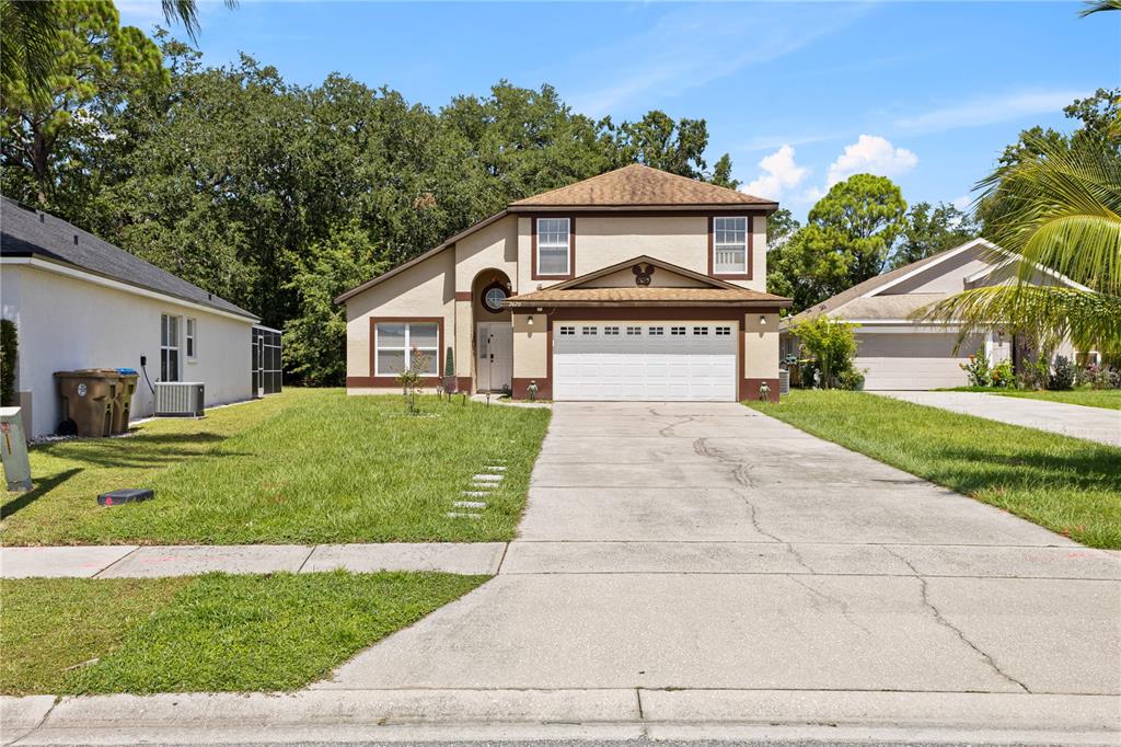 A two-story suburban house with a beige stucco exterior, brown trim, and a concrete driveway — 2629 CHATHAM CIRCLE, KISSIMMEE, FL