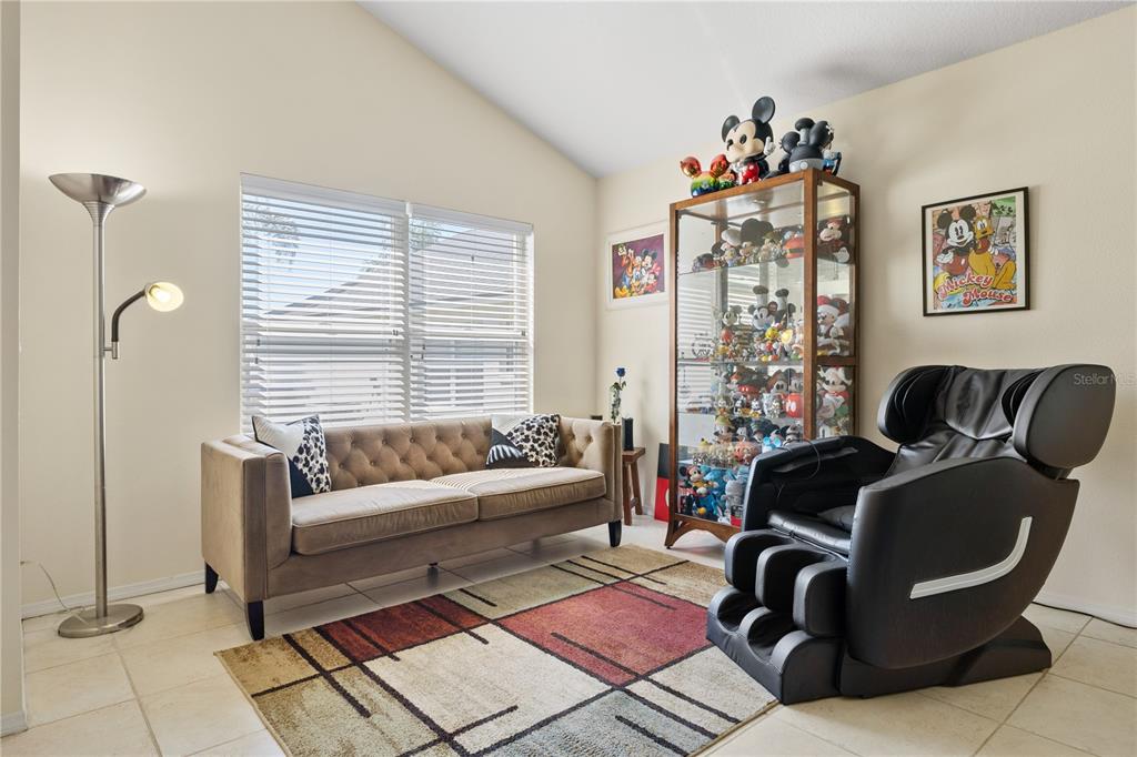 A living room features a tufted sofa, a massage chair, and a glass display cabinet — 2629 CHATHAM CIRCLE, KISSIMMEE, FL