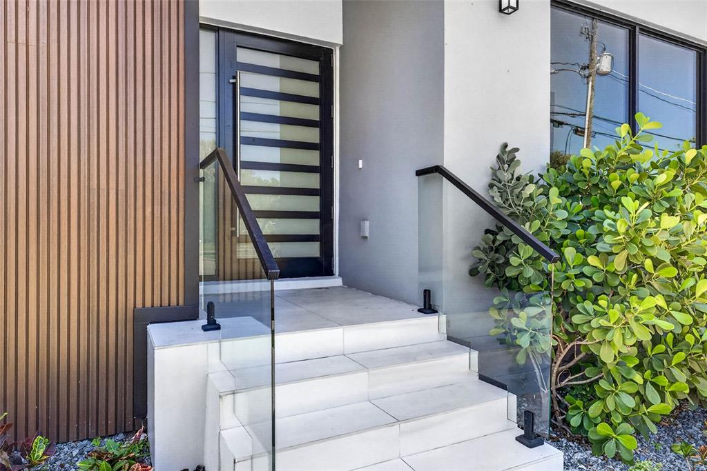 A modern front entrance features white tiled steps, glass railings, and a slatted wood wall — 4426 W EUCLID AVENUE, TAMPA, FL
