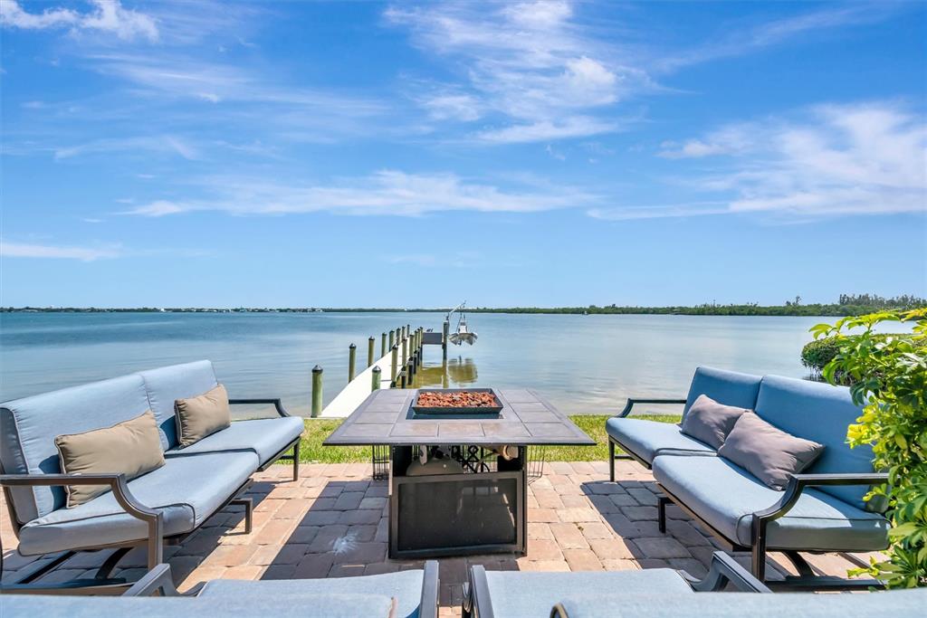A patio with two sofas and a fire pit overlooks a dock and water — 3863 CATALINA DRIVE, BRADENTON, FL