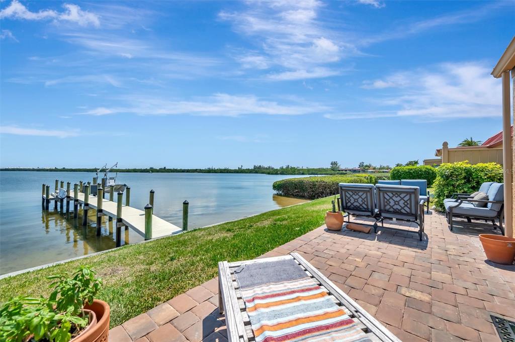 A patio with outdoor furniture overlooks a grassy lawn, a private dock, and the water — 3863 CATALINA DRIVE, BRADENTON, FL