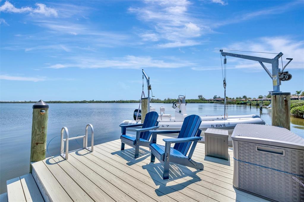 A wooden dock features two blue chairs, a boat lift, and a small boat — 3863 CATALINA DRIVE, BRADENTON, FL