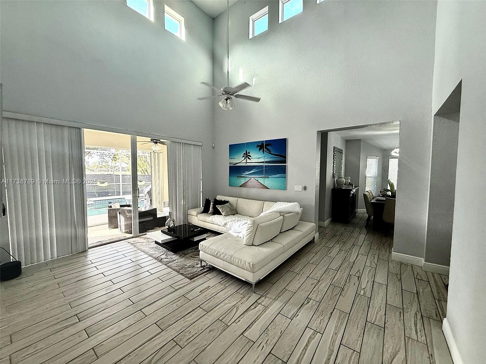 A living room features a textured accent wall, high ceilings, and a white sectional sofa — 2602 Augusta Dr, Homestead FL 33035, HOMESTEAD, FL