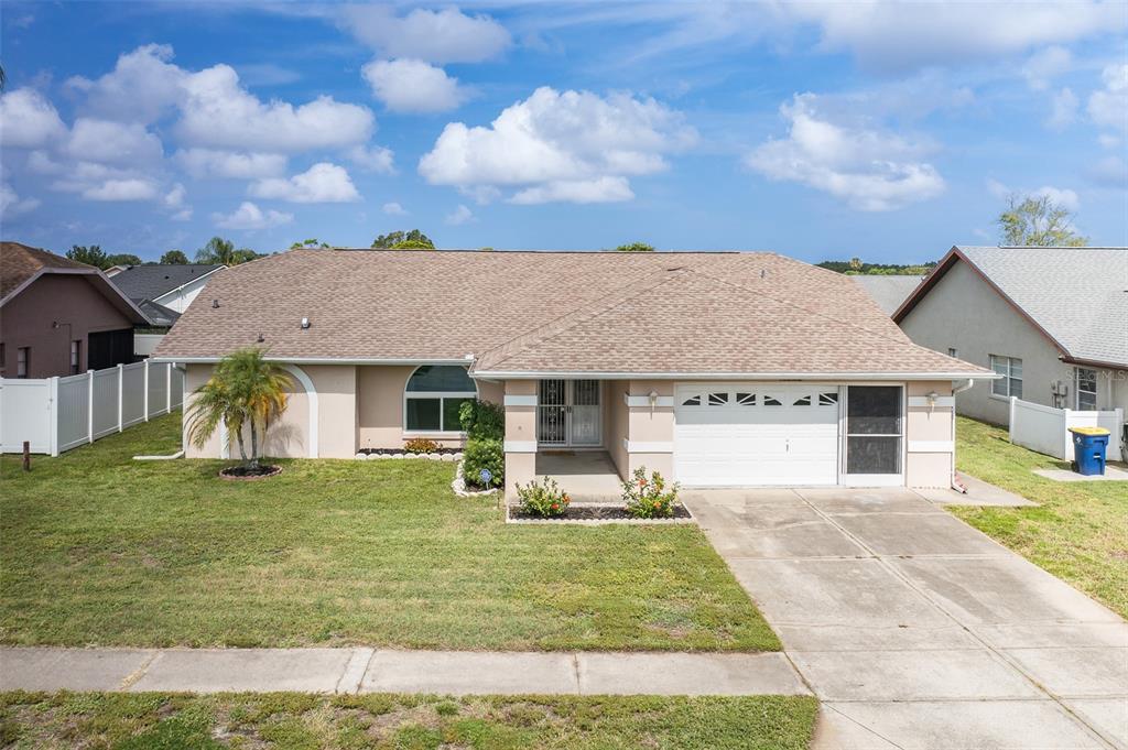 A single-story suburban house with a tan exterior, a two-car garage, and a front lawn — 4515 COUNTY BREEZE DRIVE, NEW PORT RICHEY, FL