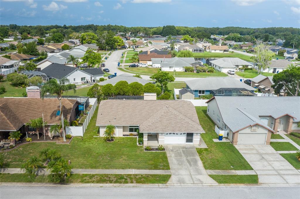 An aerial view shows a suburban house with a tan roof and a white garage — 4515 COUNTY BREEZE DRIVE, NEW PORT RICHEY, FL