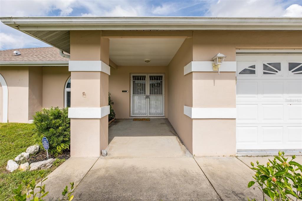 The exterior view shows a covered entryway with a double door and a garage — 4515 COUNTY BREEZE DRIVE, NEW PORT RICHEY, FL