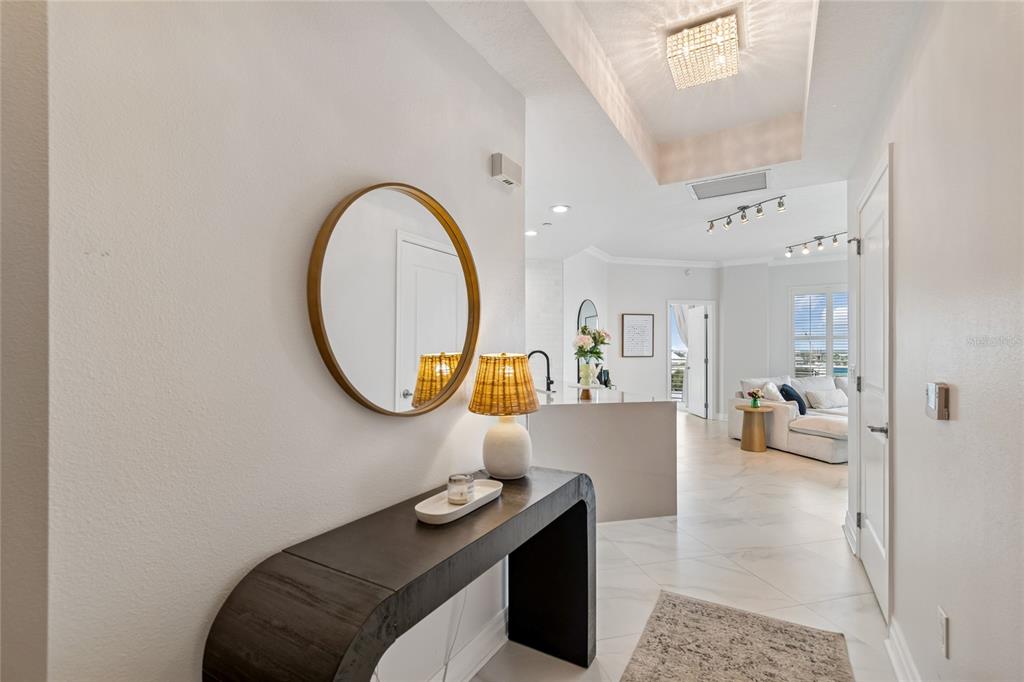 A modern entryway features a dark console table, a round mirror, and tile flooring — 449 S 12TH STREET UNIT 802, TAMPA, FL