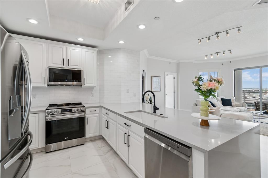A modern kitchen features white cabinets, stainless steel appliances, and a large quartz island — 449 S 12TH STREET UNIT 802, TAMPA, FL