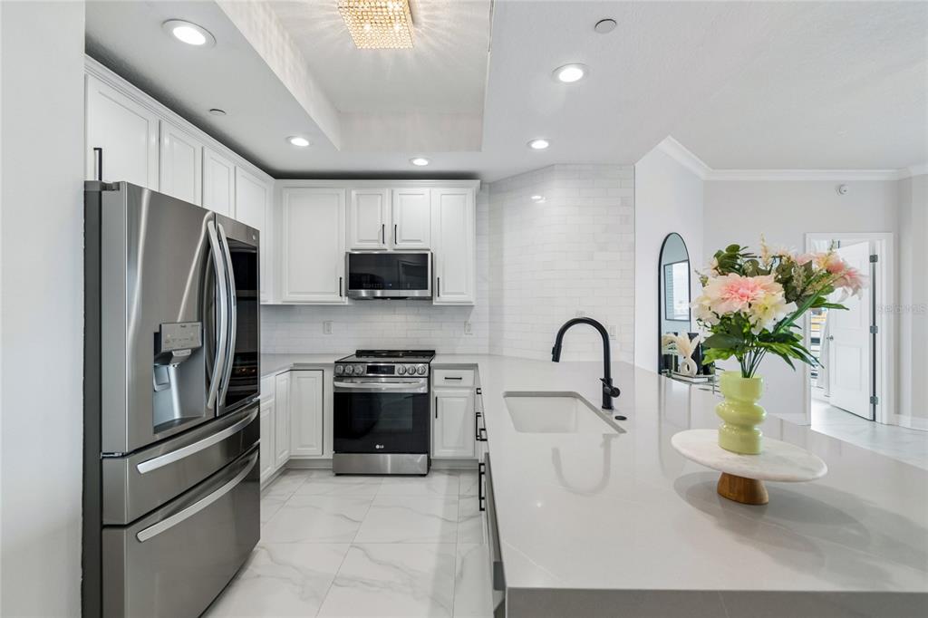 A modern kitchen features white cabinets, stainless steel appliances, and a large quartz island — 449 S 12TH STREET UNIT 802, TAMPA, FL
