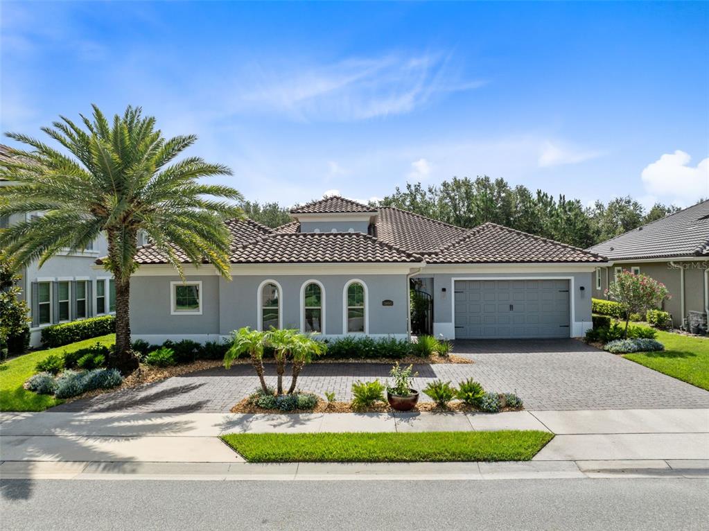 A single-story house with a gray exterior, tile roof, arched windows, and a paved driveway — 3895 GRASSLAND LOOP, LAKE MARY, FL