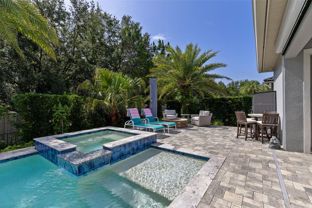 A backyard patio features a swimming pool with a spa, lounge chairs, and a fire pit — 3895 GRASSLAND LOOP, LAKE MARY, FL