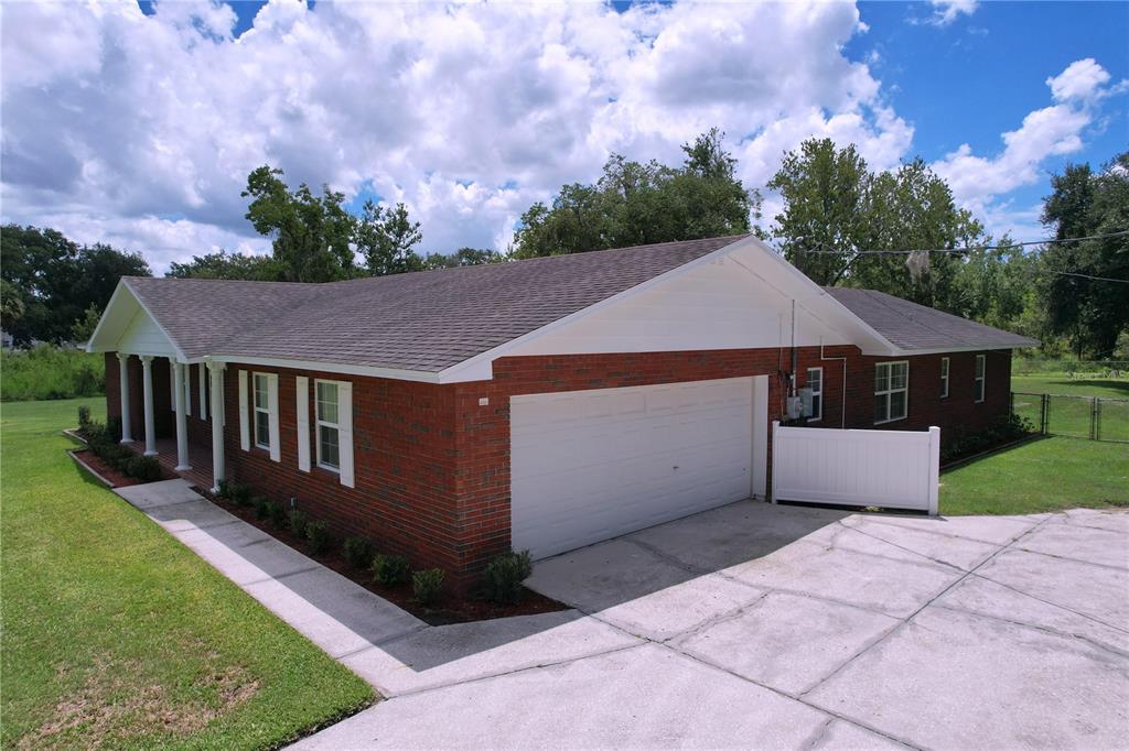 An exterior view of a brick ranch-style house with a two-car garage and white trim — 1405 KNIGHTS GRIFFIN ROAD, PLANT CITY, FL