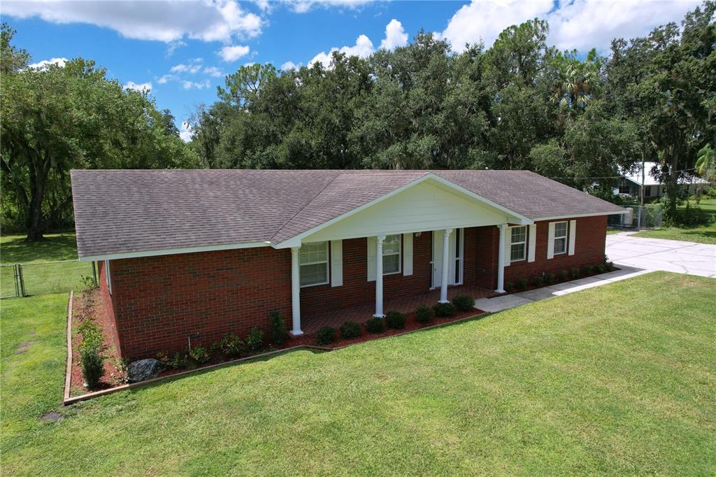 An aerial view of a single-story brick house with a covered front porch and lawn — 1405 KNIGHTS GRIFFIN ROAD, PLANT CITY, FL