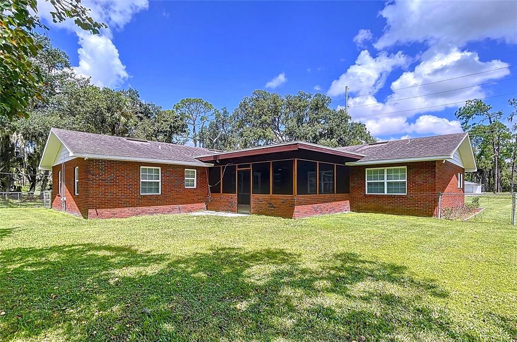A red brick house with a screened-in porch sits on a large, grassy lawn — 1405 KNIGHTS GRIFFIN ROAD, PLANT CITY, FL
