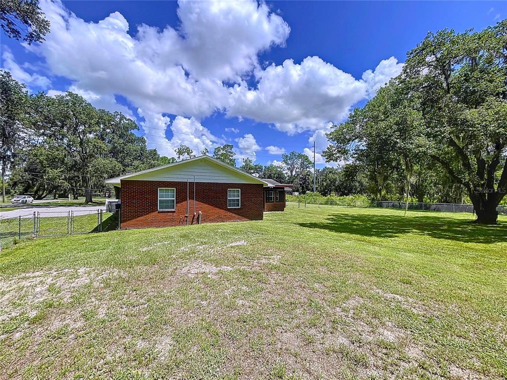 A red brick house exterior with a white gable roof sits on a grassy lot — 1405 KNIGHTS GRIFFIN ROAD, PLANT CITY, FL