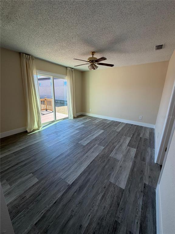 An empty room with gray wood-look flooring, a ceiling fan, and a sliding glass door — 2689 COURTLAND BOULEVARD, DELTONA, FL