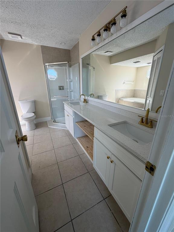 A bathroom features a double vanity with white cabinets, gold fixtures, and a glass shower — 2689 COURTLAND BOULEVARD, DELTONA, FL