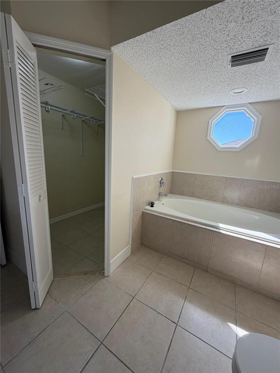 A bathroom features a tiled soaking tub, a walk-in closet, and an octagonal window — 2689 COURTLAND BOULEVARD, DELTONA, FL