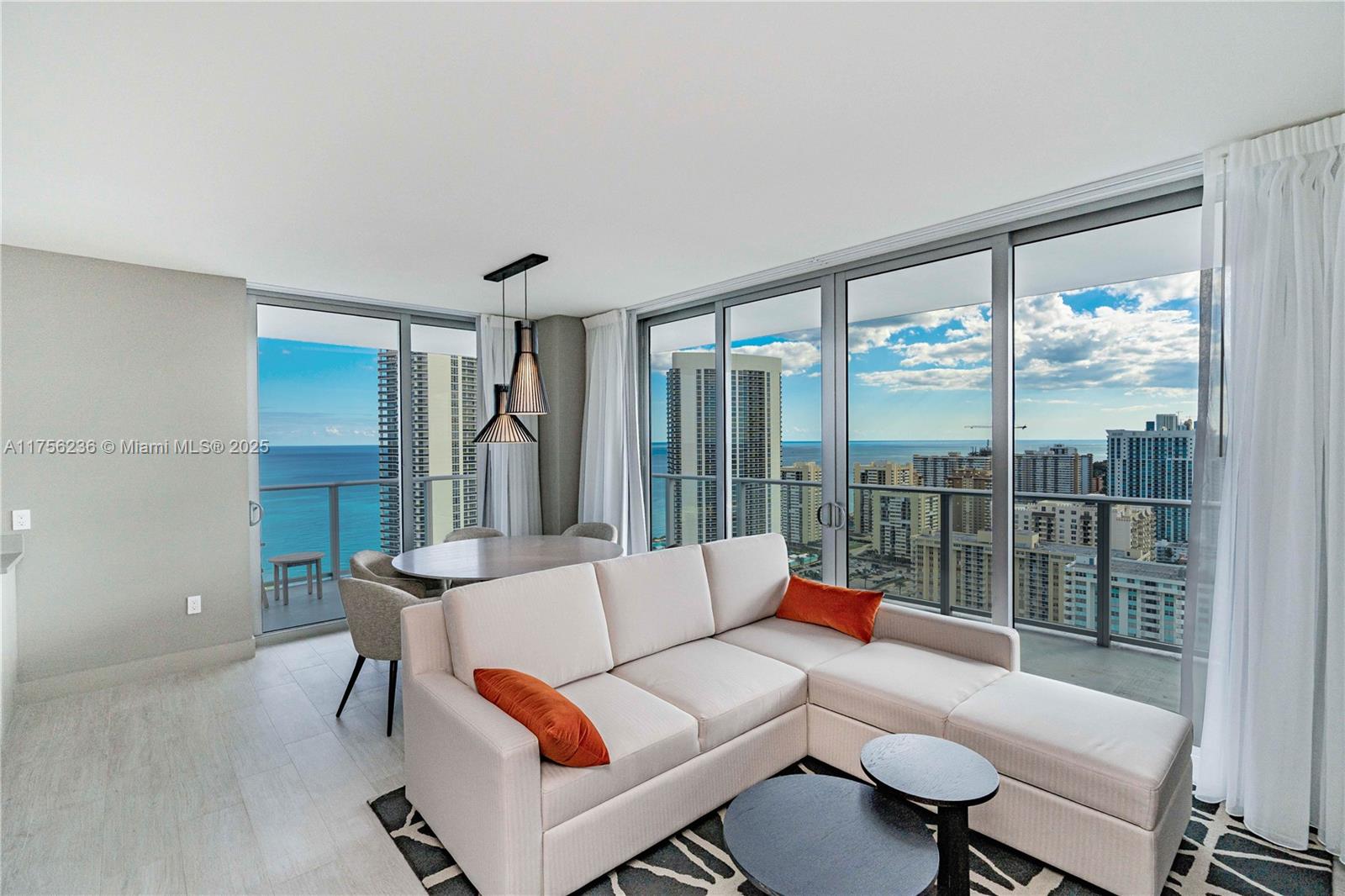 A living and dining area features a sectional sofa, round table, and floor-to-ceiling windows — 4010 S Ocean Dr # R1609, Hollywood FL 33019, HOLLYWOOD, FL