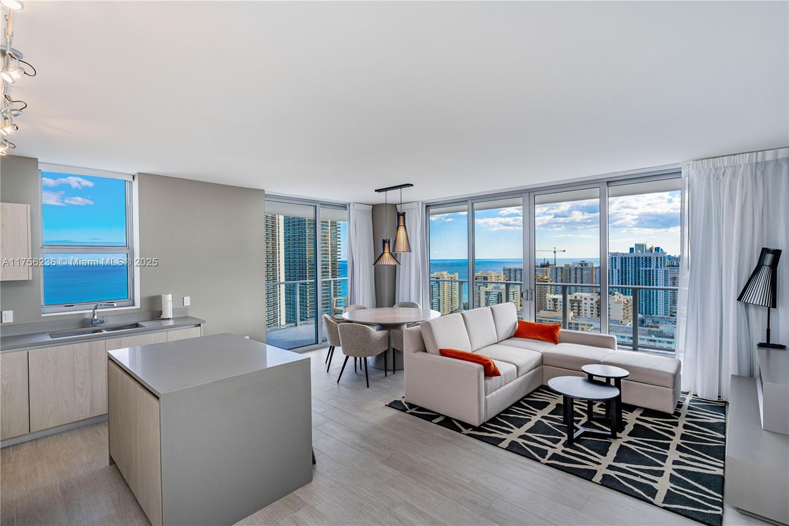 An open-concept living and dining area features a kitchen island, floor-to-ceiling windows, and ocean views — 4010 S Ocean Dr # R1609, Hollywood FL 33019, HOLLYWOOD, FL