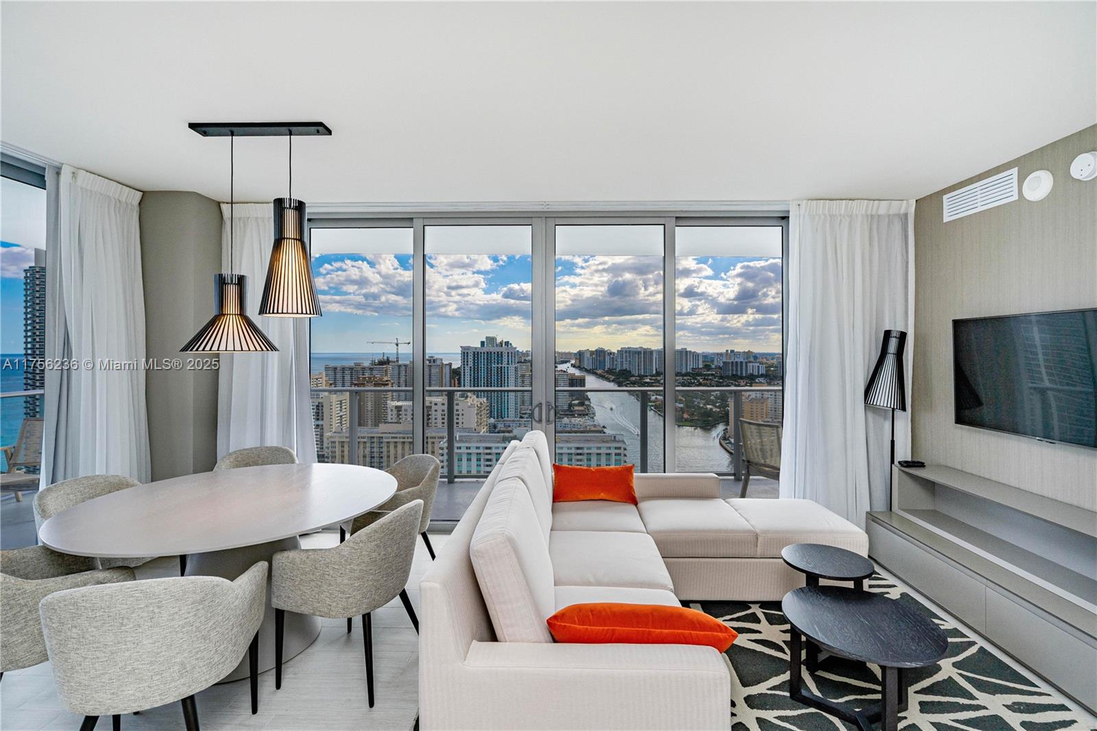A modern living and dining area features floor-to-ceiling windows with a city and water view — 4010 S Ocean Dr # R1609, Hollywood FL 33019, HOLLYWOOD, FL