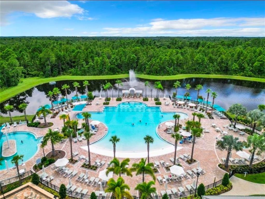 An aerial view of a large resort-style swimming pool surrounded by palm trees and landscaping — 6354 SHIMMERING SHORES LANE, ST CLOUD, FL