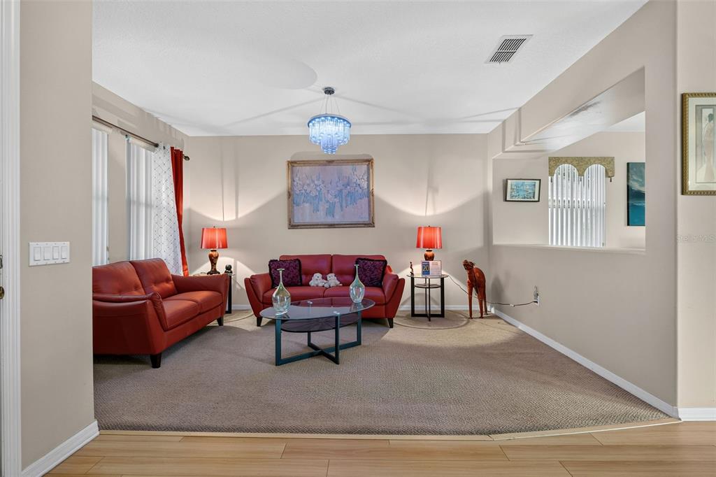 A living room features two red sofas, a glass coffee table, and a crystal chandelier — 16525 SUNRISE VISTA DRIVE, CLERMONT, FL