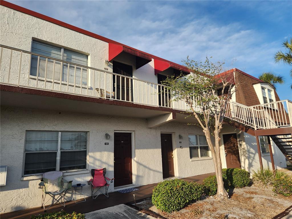 A two-story apartment building with stucco walls, brown doors, and an exterior metal staircase — 9101 W HILLSBOROUGH AVENUE UNIT I209, TAMPA, FL