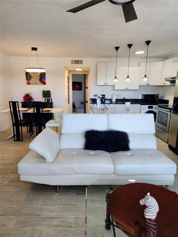 A white leather sofa sits in an open-concept living area with a kitchen and dining space — 9101 W HILLSBOROUGH AVENUE UNIT I209, TAMPA, FL