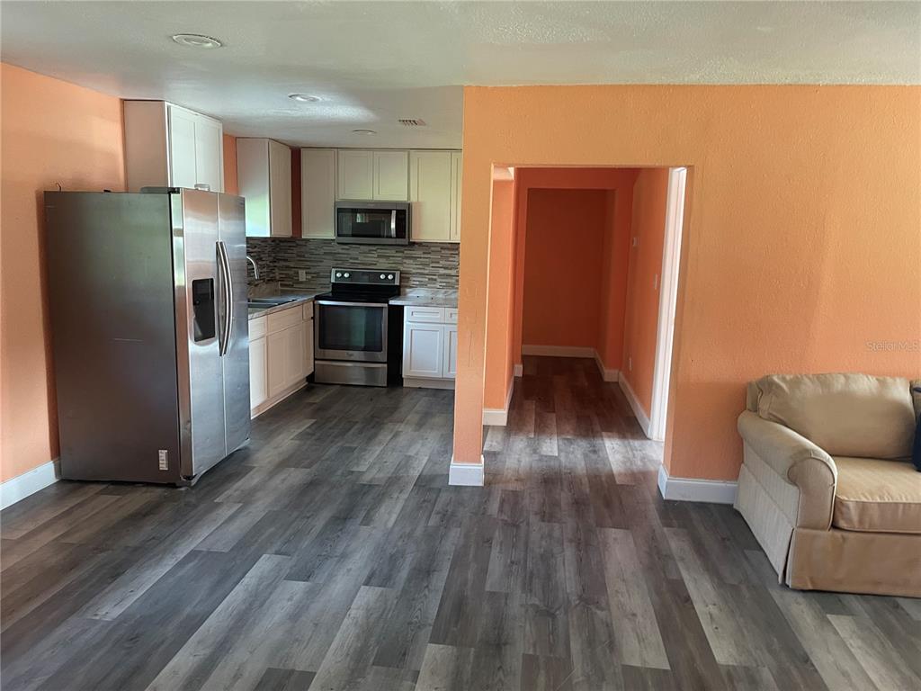 A kitchen with white cabinets, stainless steel appliances, marble-look countertops, and a tiled backsplash — 1701 36TH STREET NW, WINTER HAVEN, FL