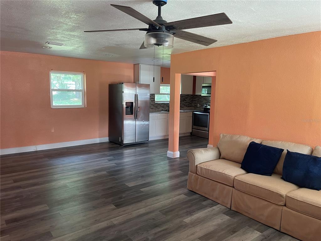 A kitchen features stainless steel appliances, white cabinetry, a tiled backsplash, and wood-look flooring — 1701 36TH STREET NW, WINTER HAVEN, FL