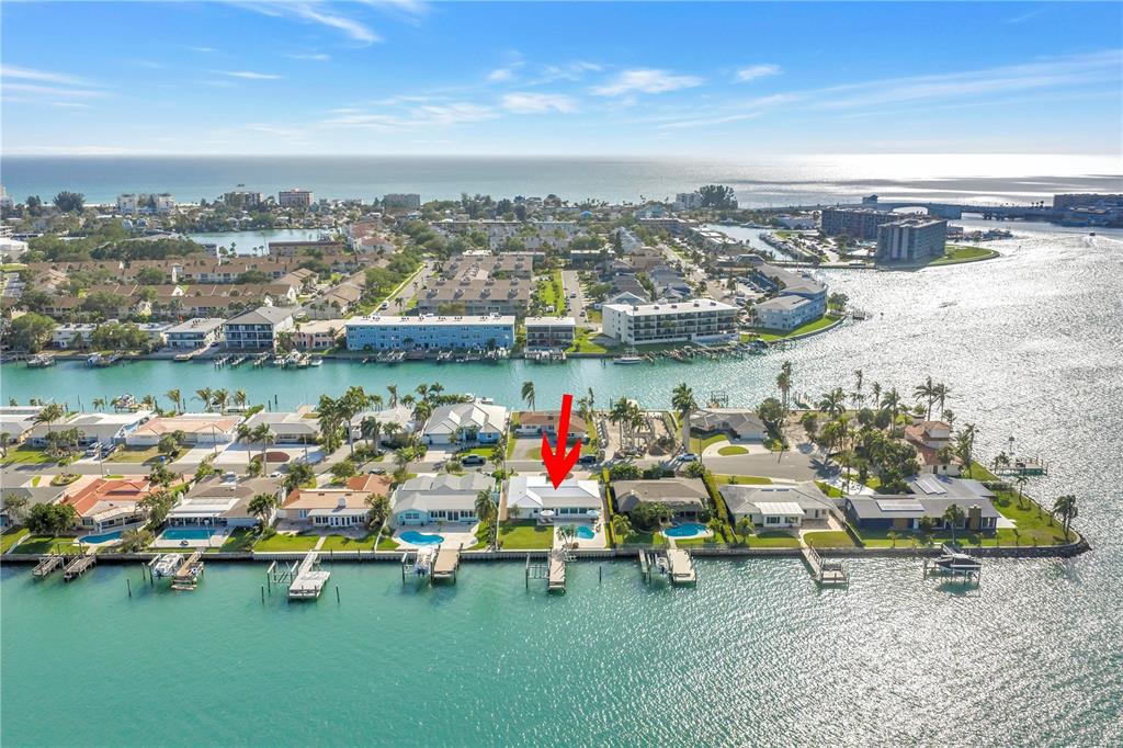 An aerial view shows a waterfront house with a pool and dock on a canal — 12475 4TH STREET E, TREASURE ISLAND, FL