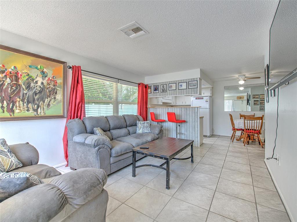 A living room with tile floors, a grey sofa, a coffee table, and a kitchen bar — 4313 TAHITIAN GARDENS CIRCLE UNIT K, HOLIDAY, FL