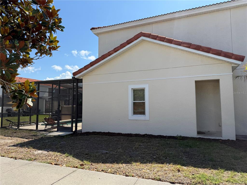 The exterior of a beige house features a tiled roof, a window, and a screened lanai — 4573 ADA LANE, KISSIMMEE, FL
