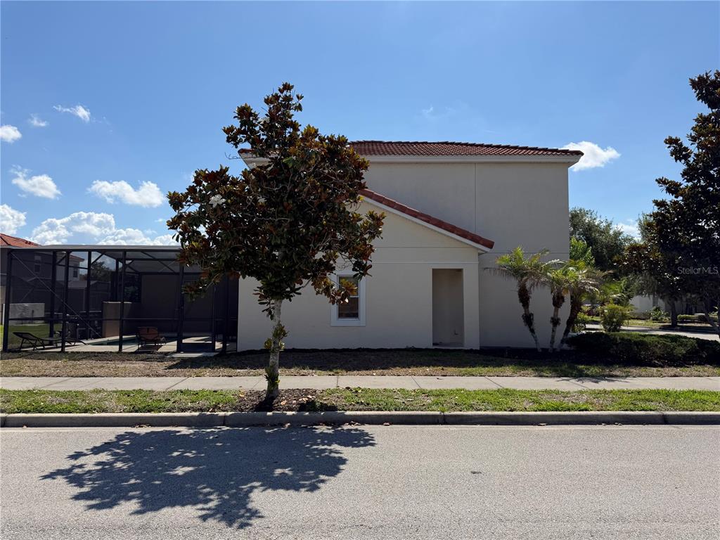 A two-story house with a screened-in pool area and a small tree in the yard — 4573 ADA LANE, KISSIMMEE, FL