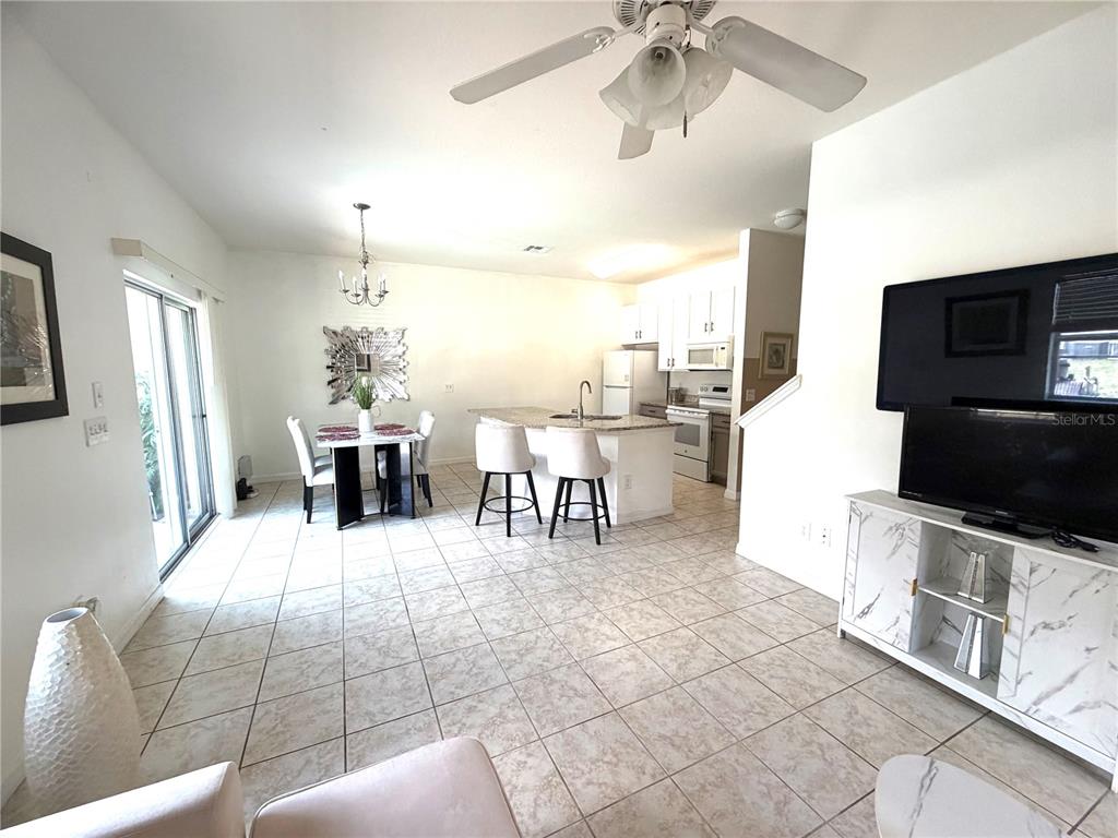 An open-concept kitchen and dining area features tile flooring, white cabinetry, and a ceiling fan — 4573 ADA LANE, KISSIMMEE, FL