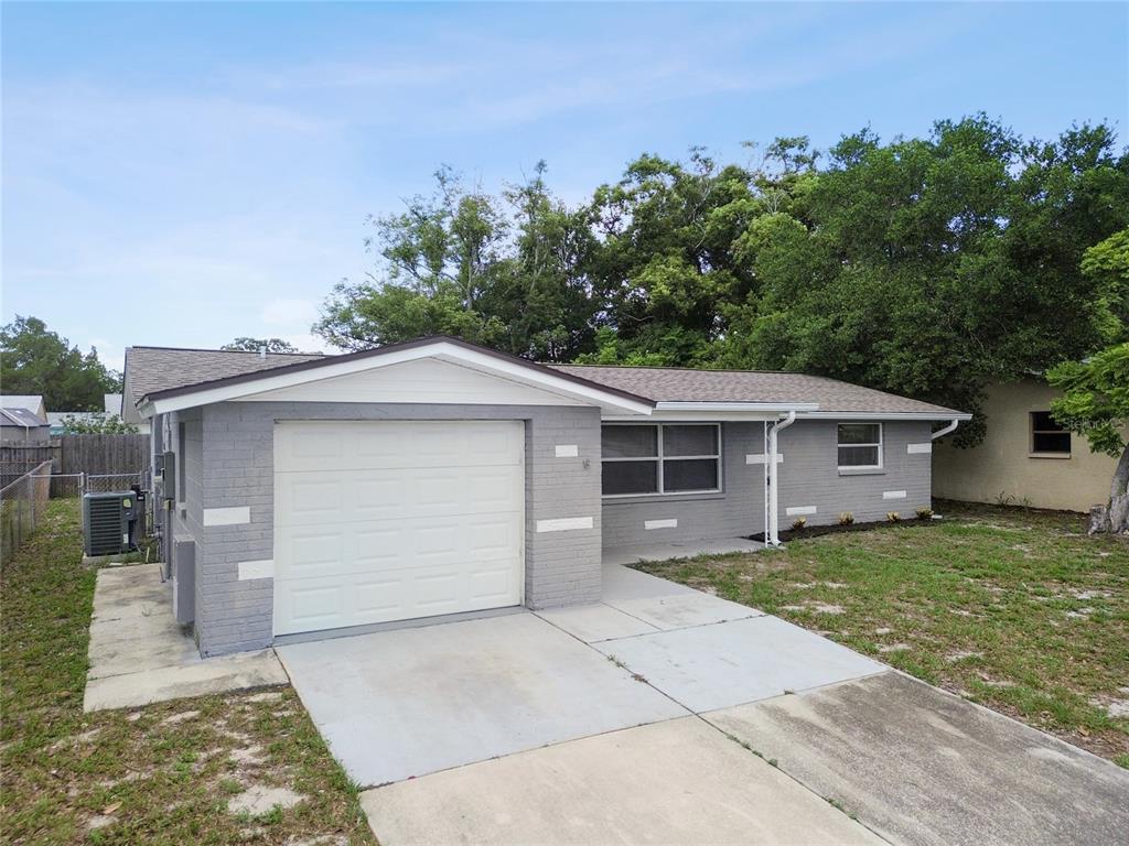 A single-story gray brick house features a one-car garage and a concrete driveway — 7721 ARBORDALE DRIVE, PORT RICHEY, FL