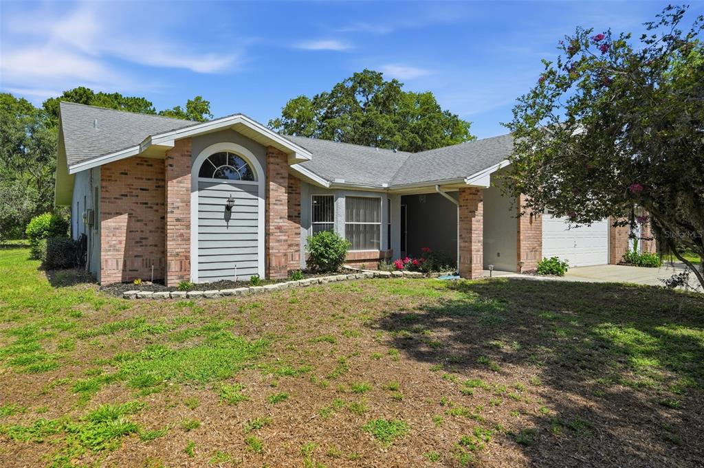 A single-story brick and siding house with a front-facing garage and a landscaped yard — 18451 WINDING OAKS BOULEVARD, HUDSON, FL