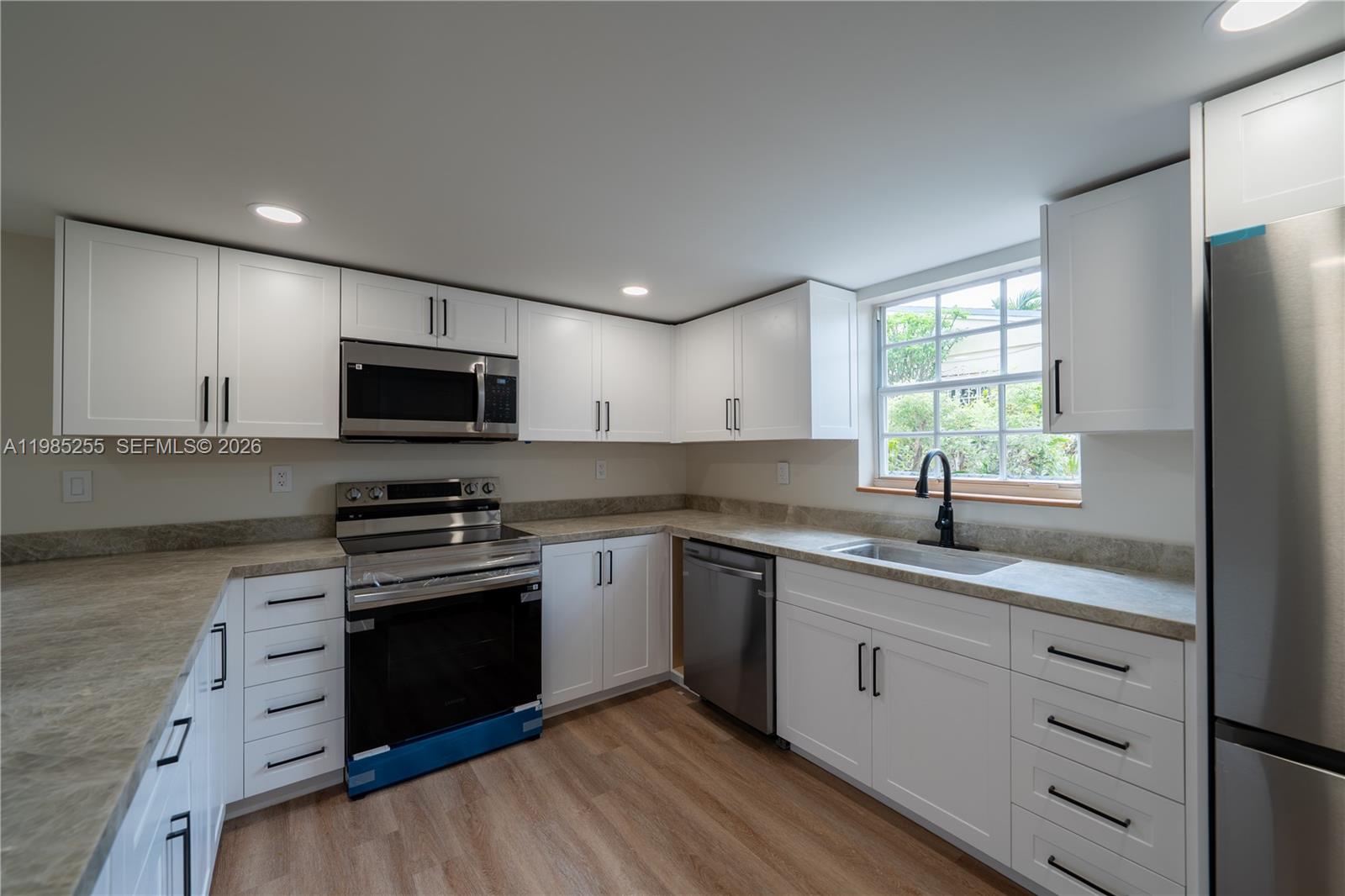 A kitchen features white cabinets, stainless steel appliances, a window, and light-colored countertops — 370 Flagami Blvd, Miami FL 33144, MIAMI, FL
