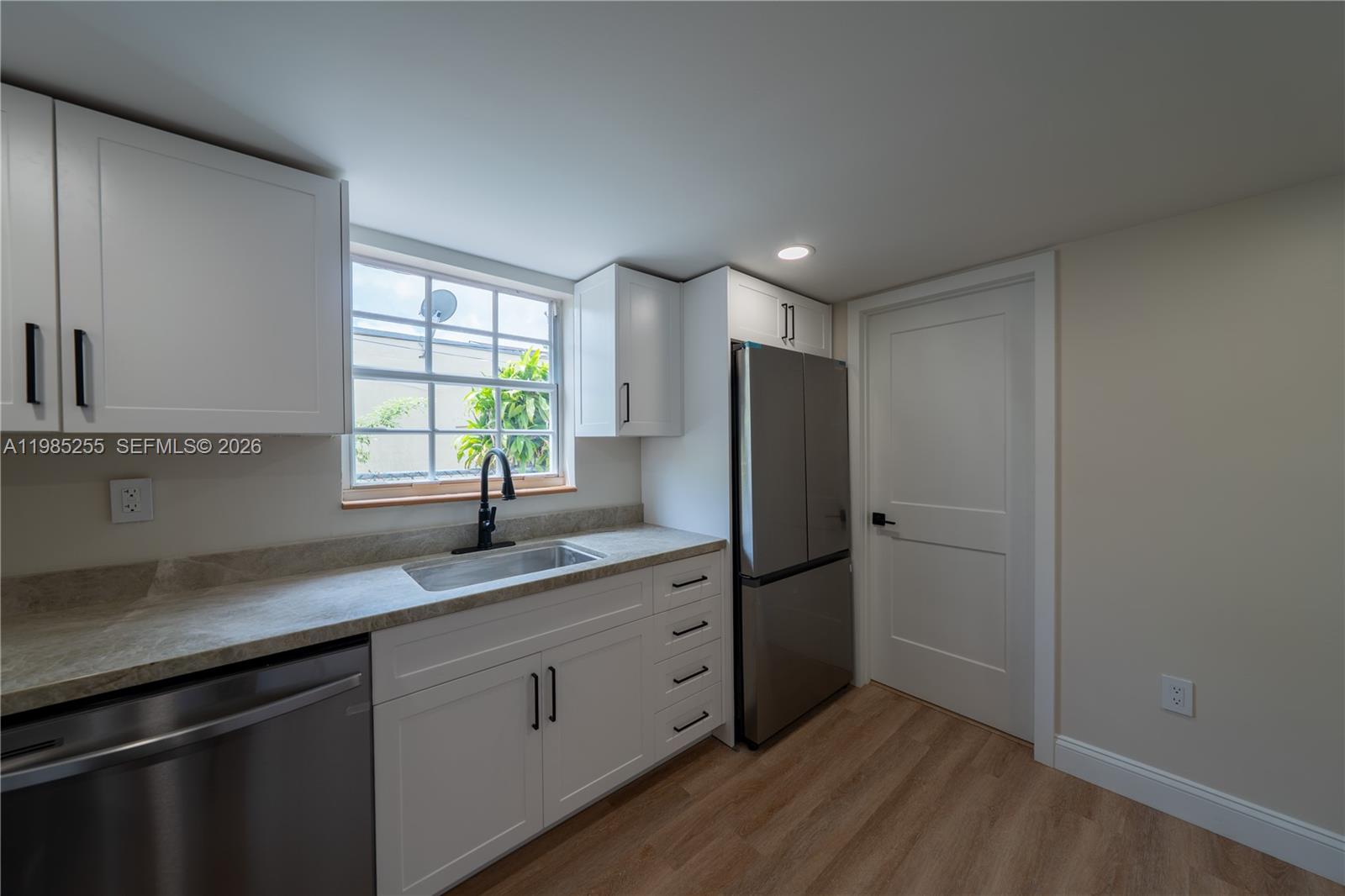 A kitchen features white cabinets, stainless steel appliances, a window, and light wood flooring — 370 Flagami Blvd, Miami FL 33144, MIAMI, FL