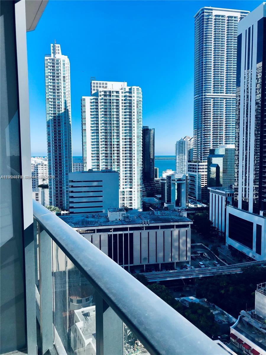 A high-angle view from a balcony overlooking a dense city skyline and the ocean — 45 SW 9th St # 2004, Miami FL 33130, MIAMI, FL