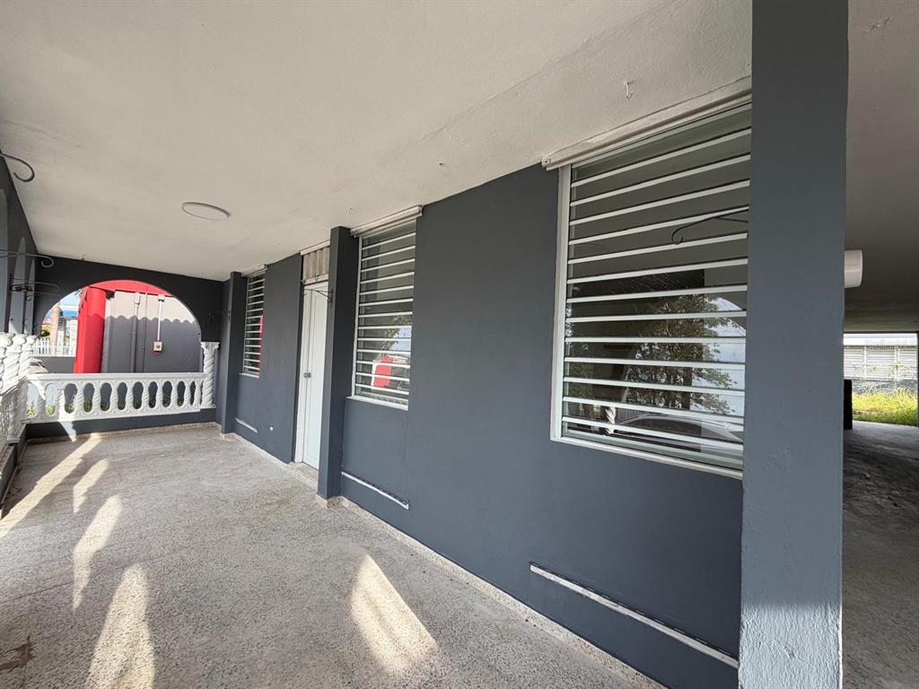A covered porch with gray walls, white window security bars, and a white balustrade — Villa Carolina 205-13 N 510, CAROLINA, PR